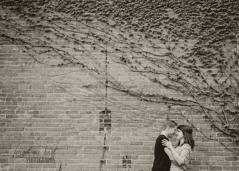 wide black and white photo of couple on ivy wall