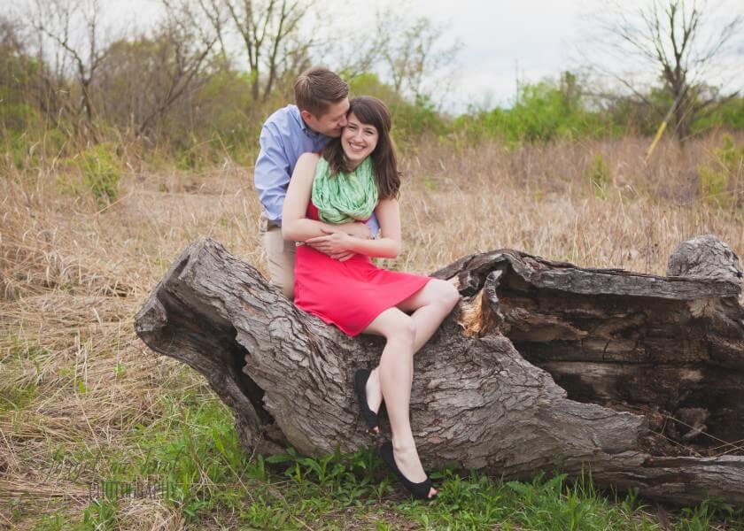 engaged couple sitting on tree stump at grange audubon center