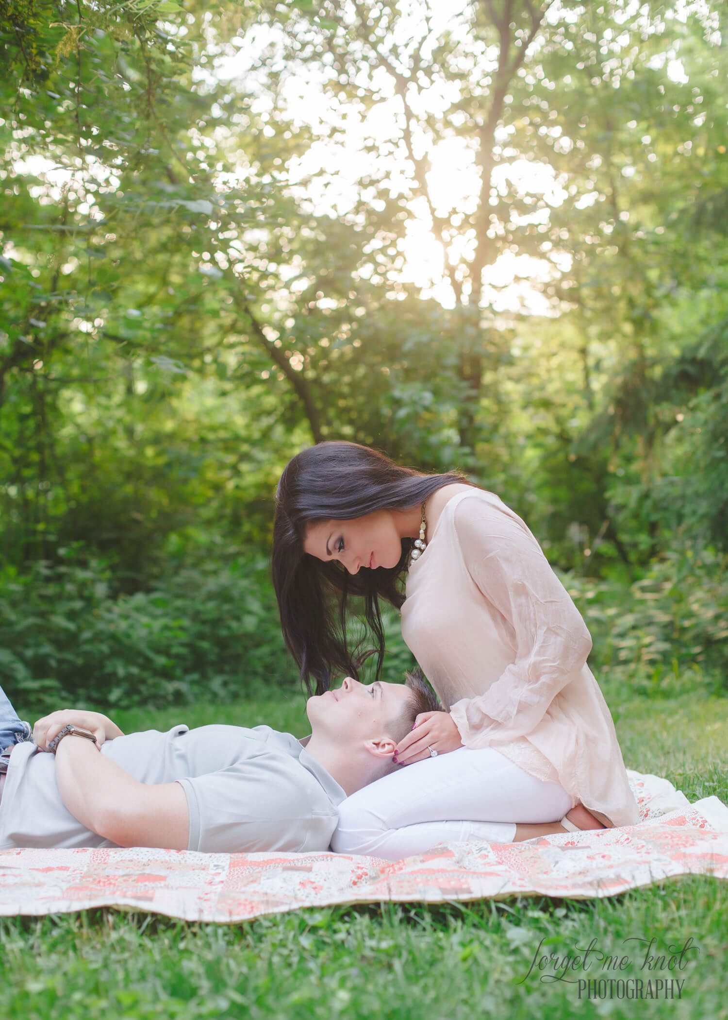 engaged couple looking at each other while laying in grass