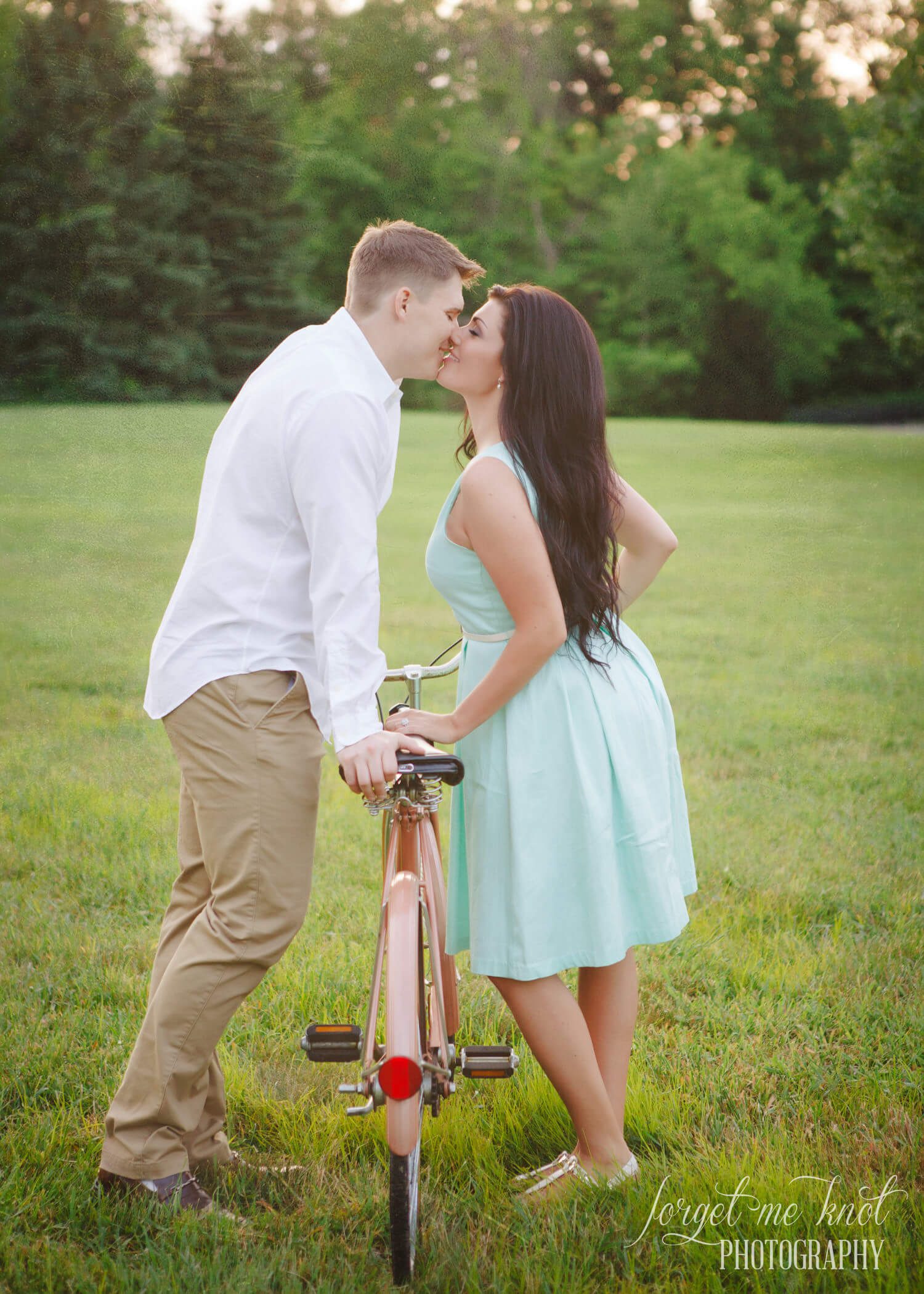 Vintage Engagement Photography session of couple kissing over vintage bicycle