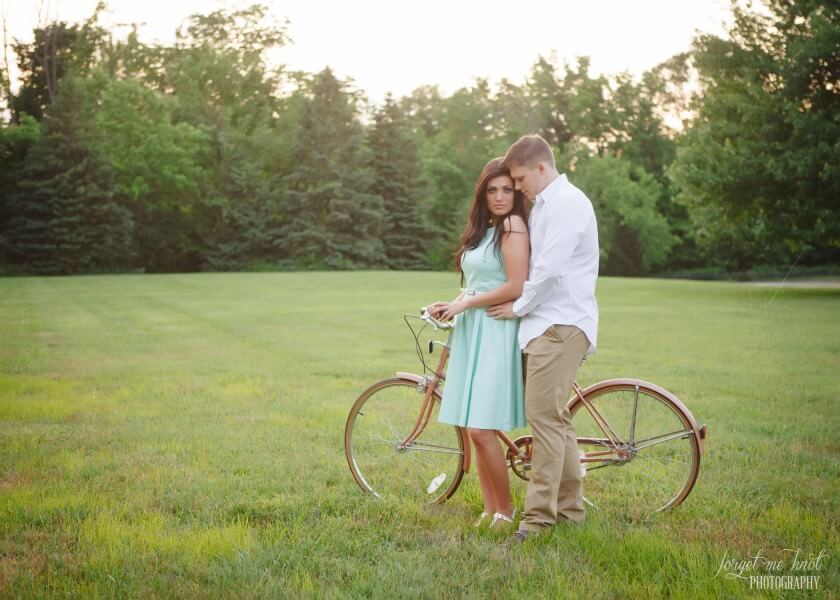engaged couple in field with vintage bicycle