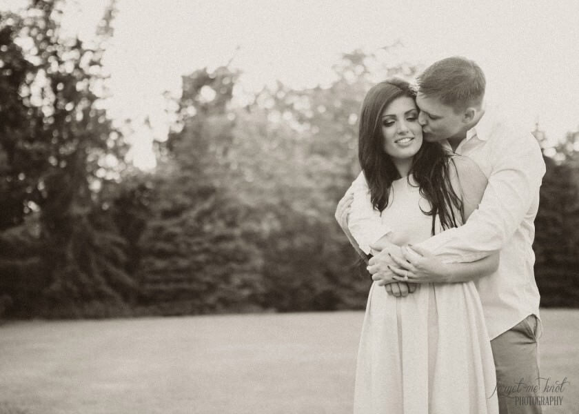 black and white photo of groom to be kissing fiance on cheek