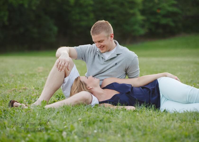 engaged couple sitting in grass at park