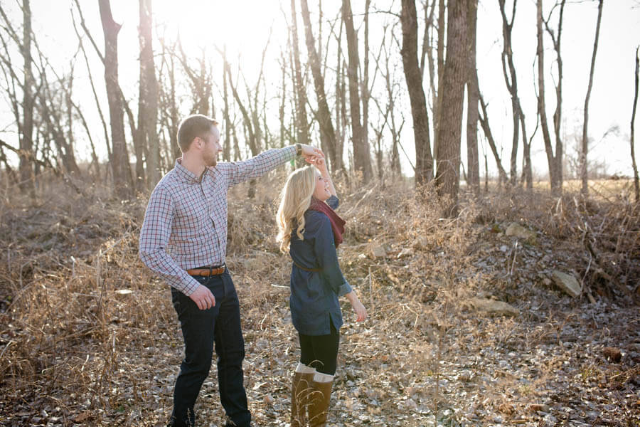 engagement photo of couple twirling in winter trees