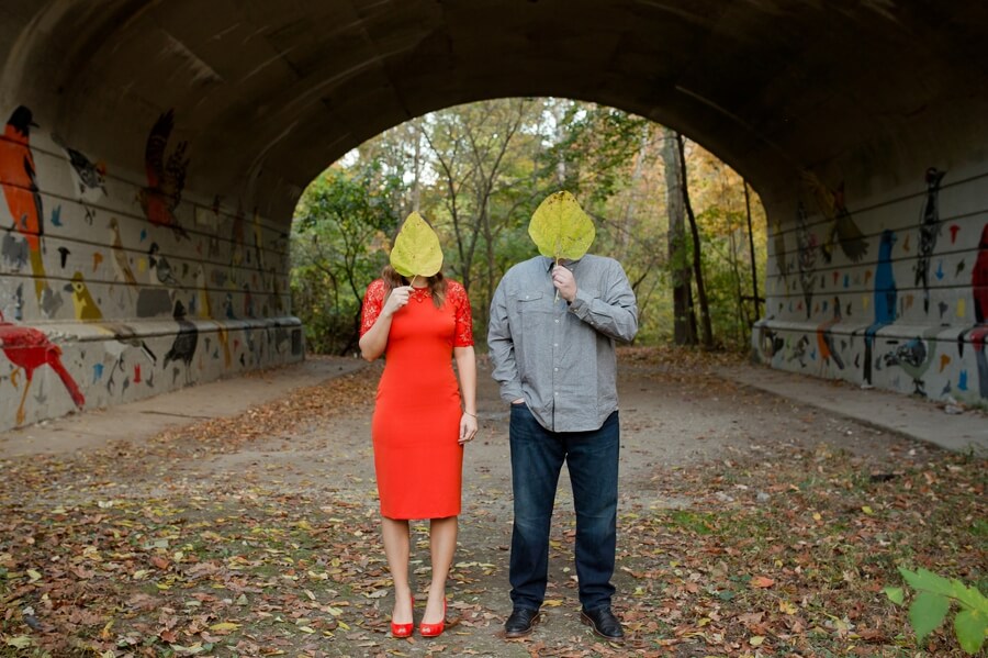 engaged couple covering their faces behind leaves at Stauf's Grandview Engagement