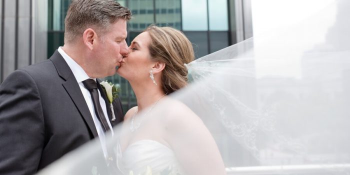 bride and groom kissing with veil