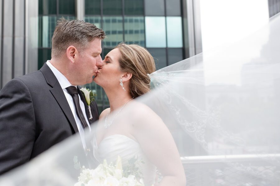 bride and groom kissing with veil