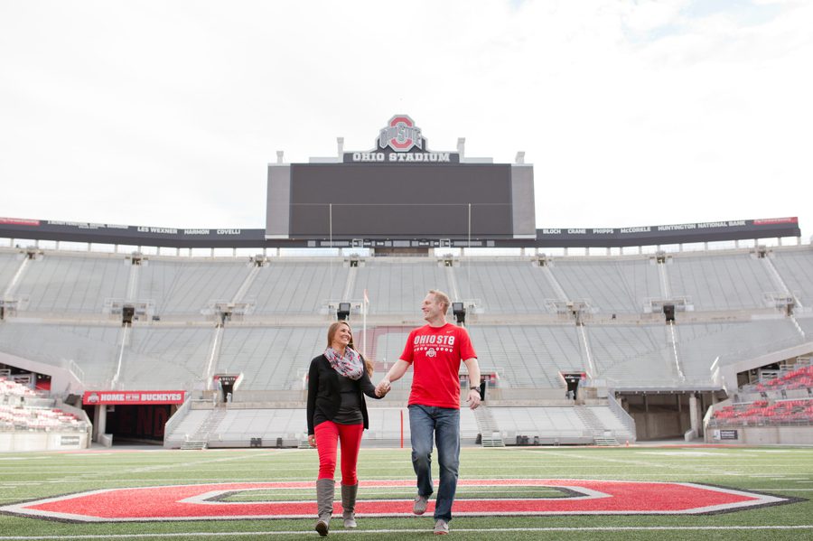 engaged couple running on Ohio State University football stadium