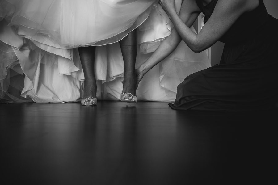 bridesmaid helping bride put on shoes