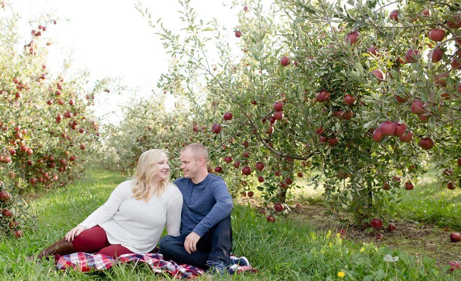 engaged couple smiling at each other at apple orchard
