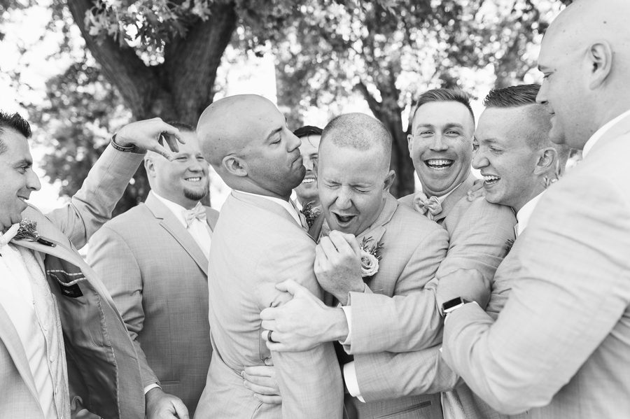 black and white photo of groomsmen teasing groom