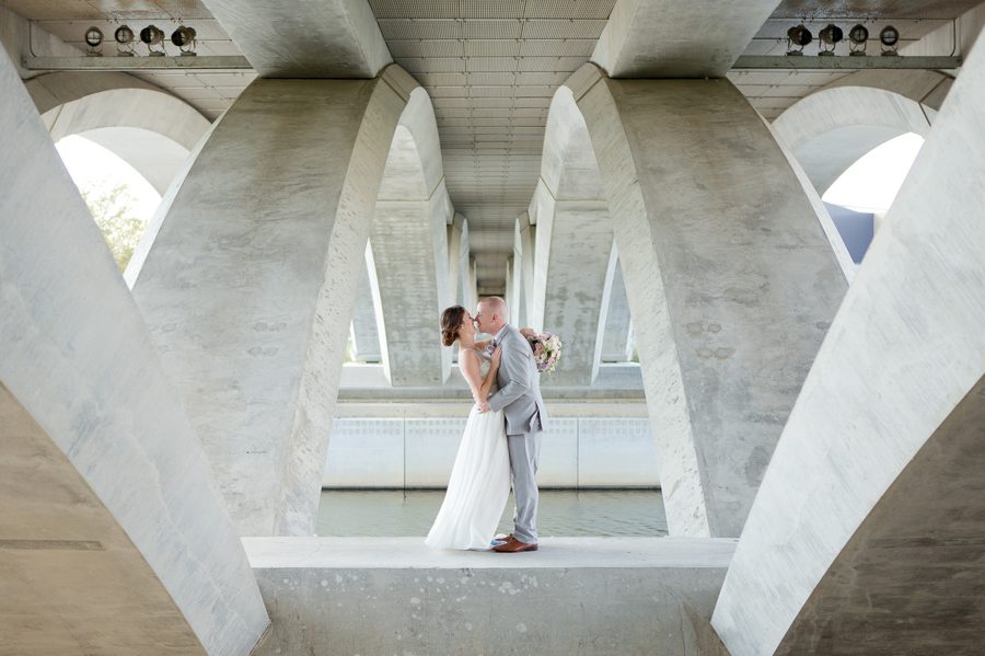 bride and groom kissing under scioto mile bridge