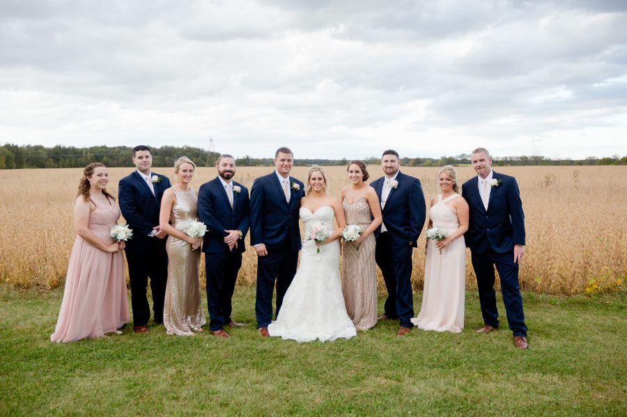 navy and blush wedding party in front of a field