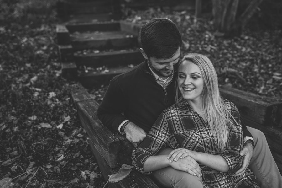 black and white photo of engaged couple laughing on stairs