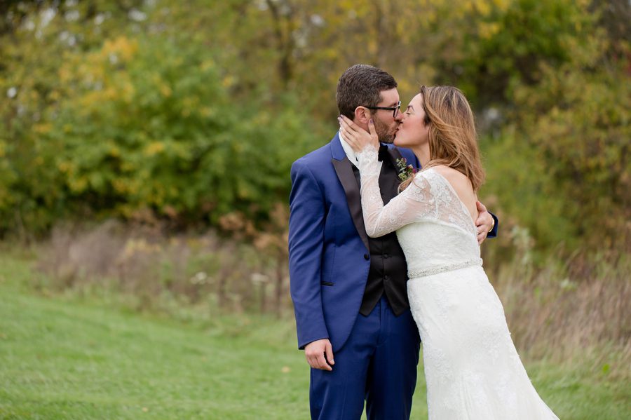 bride kissing her groom in field