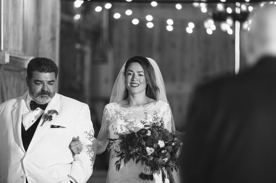 black and white photo of bride walking down aisle