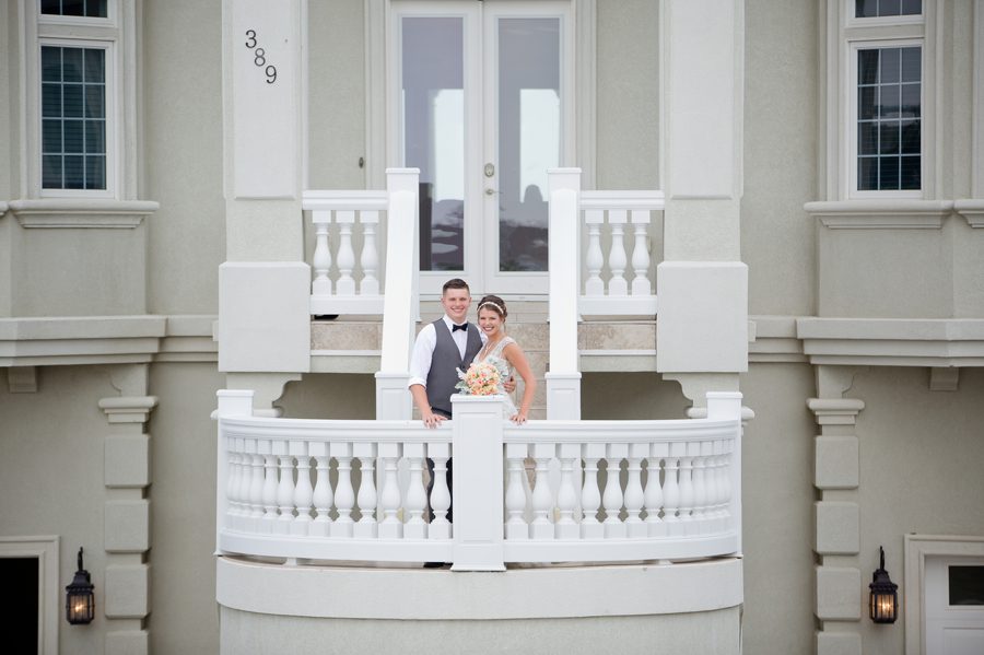 bride and groom smiling on porch of beach house