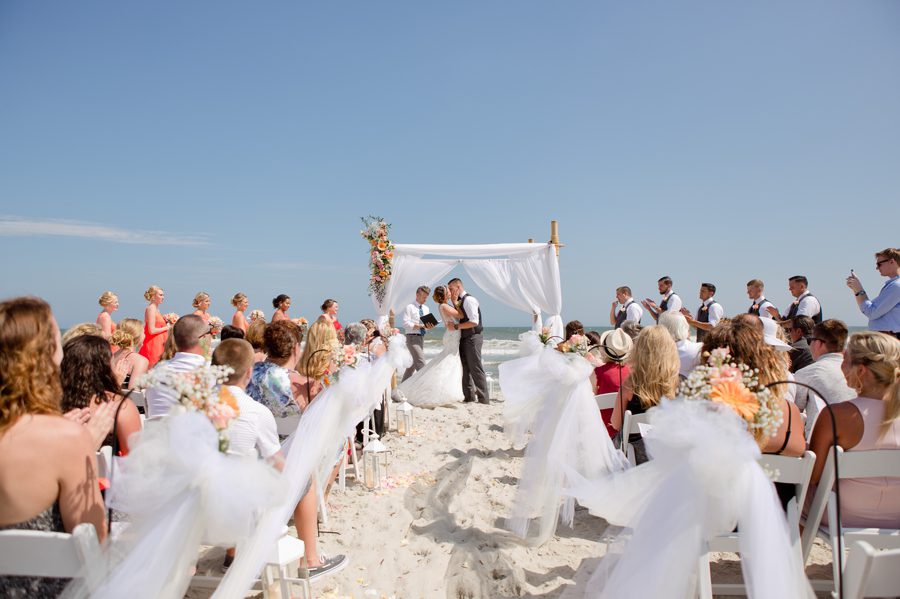 first kiss of bride and groom at ocean isle beach wedding