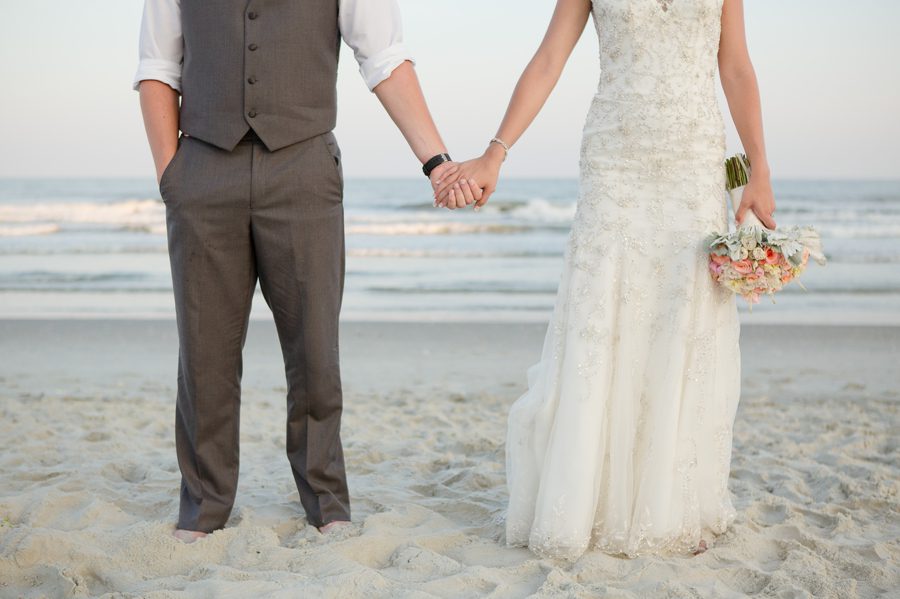 bride and groom holding hands on beach