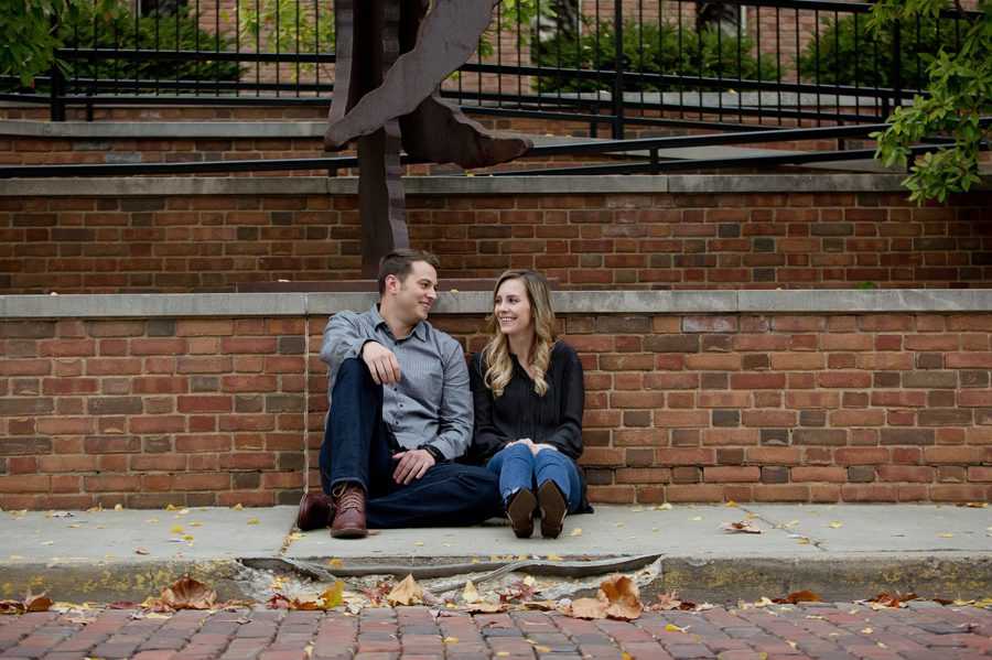 engaged couple sitting on sidewalk of Ohio University