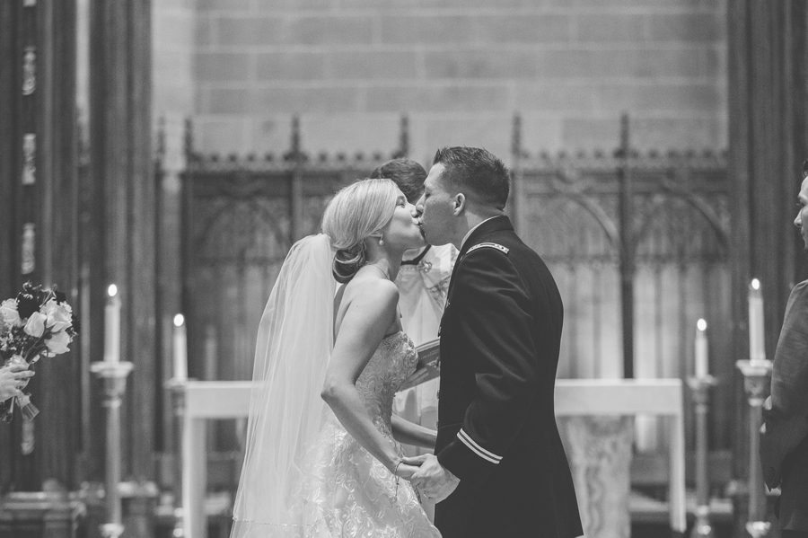 black and white photo of bride and groom sharing first kiss