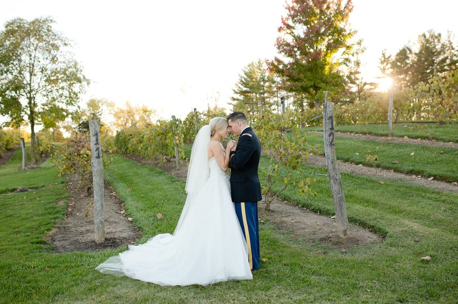 married couple with foreheads together in vineyard