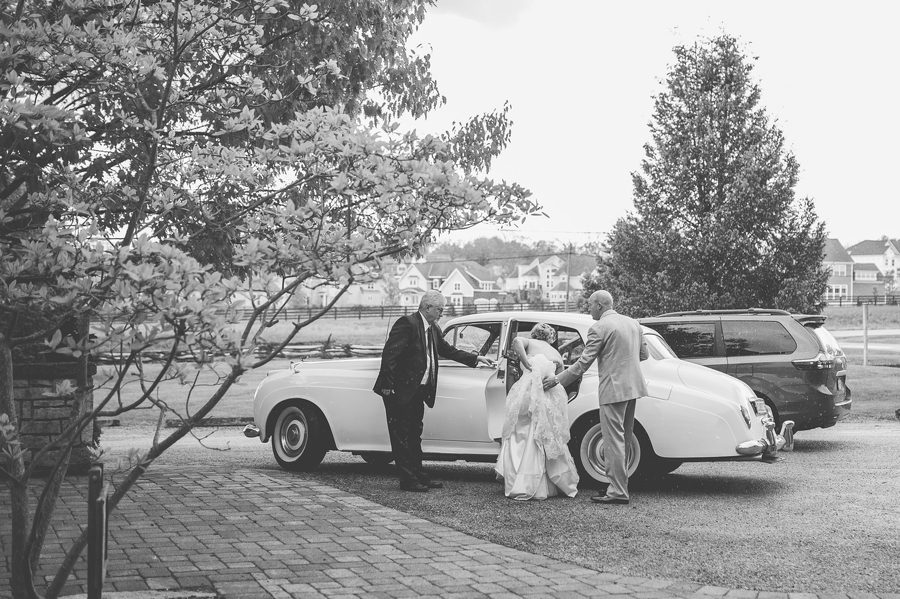 groom helping bride get in bentley car