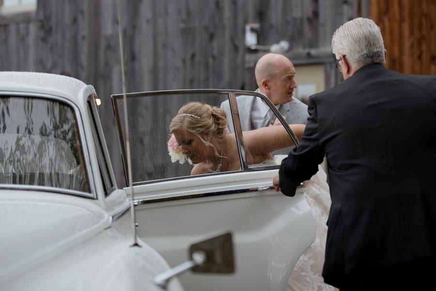 bride getting in bentley car in rain