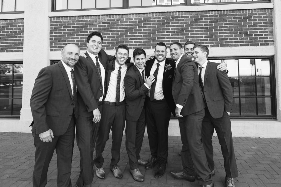 black and white photo of groomsmen hugging groom