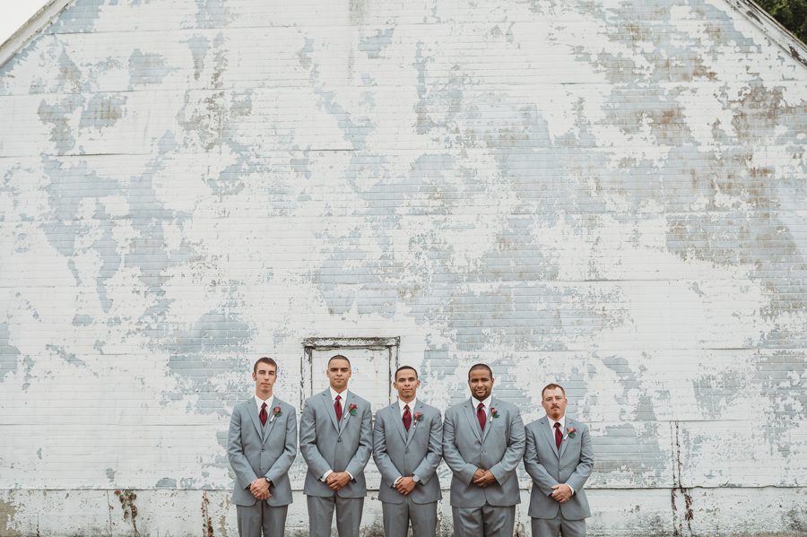 groom with groomsmen in front of white brick building