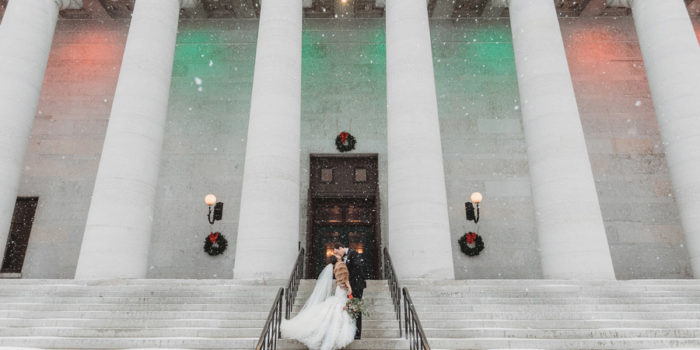 wide photo of couple kissing at The Ohio Statehouse in snow