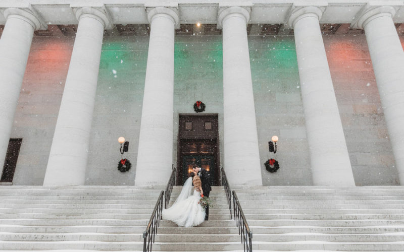 wide photo of couple kissing at The Ohio Statehouse in snow