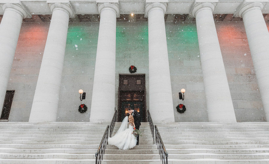 wide photo of couple kissing at The Ohio Statehouse in snow