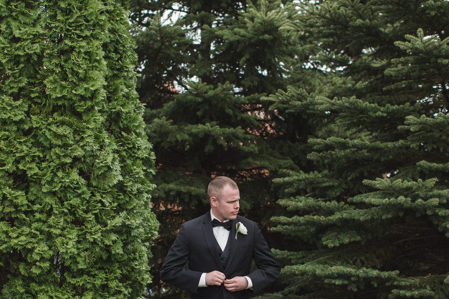 groom buttoning tuxedo jacket