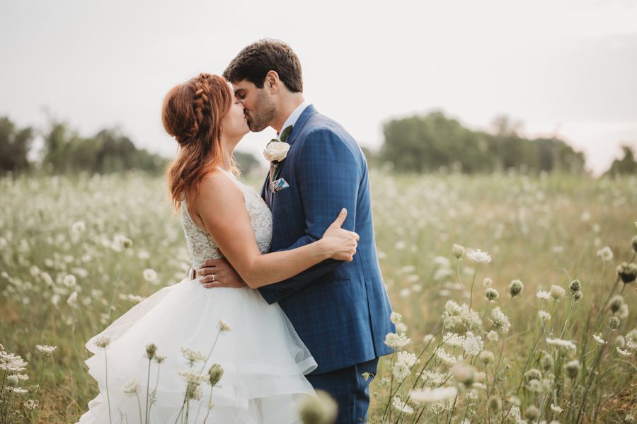 married couple kissing in flower field