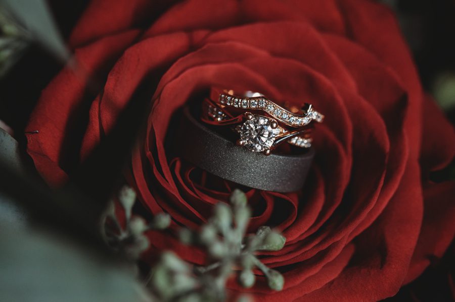 rose gold wedding band and engagement ring on a red rose