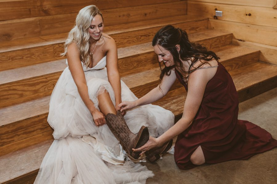 bridesmaid helping bride put on cowboy boots