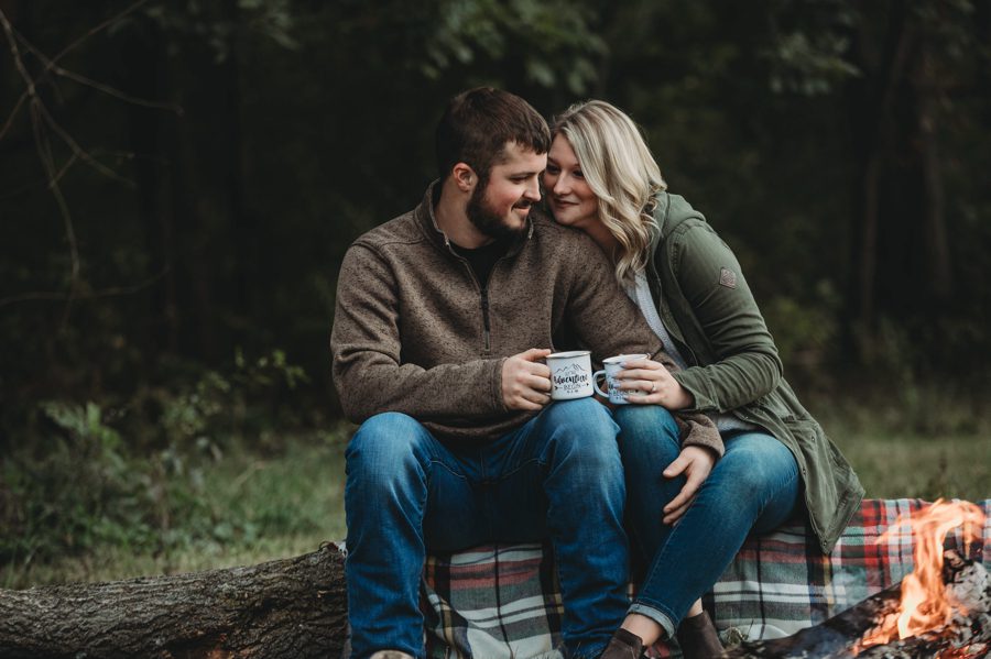 engaged couple sitting plaid blanket on log by a bonfire in Mount Vernon Ohio