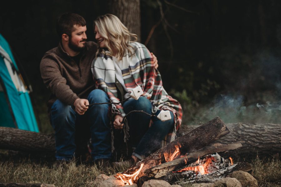 close up photo of engaged couple roasting marshmallows at Camping Engagement Photos