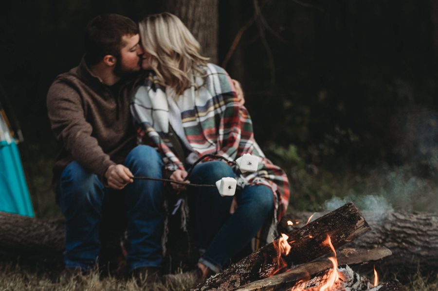 engaged couple kissing whole roasting marshmallows at bonfire in Mount Vernon Ohio