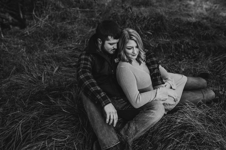 groom to be with arm around fiancé while sitting in tall grass in Mount Vernon Ohio