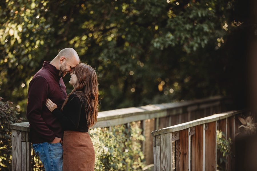 engaged couple on bridge walking path with foreheads together at Engagement Photos at Grange Audubon