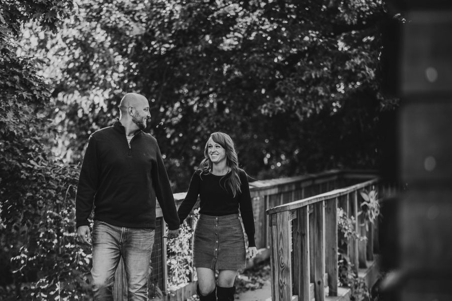 black and white image of couple smiling and holding hands at Engagement Photos at Grange Audubon