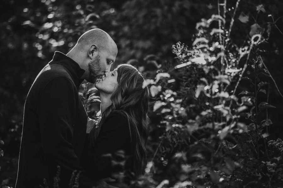 black and white image of engaged couple about to kiss in a field