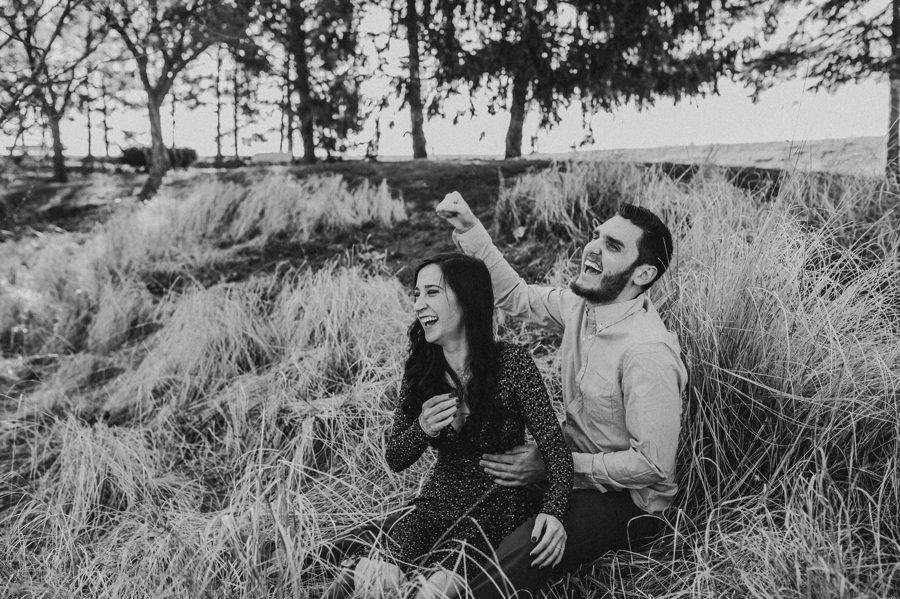 black and white image of engaged couple laughing and cheering