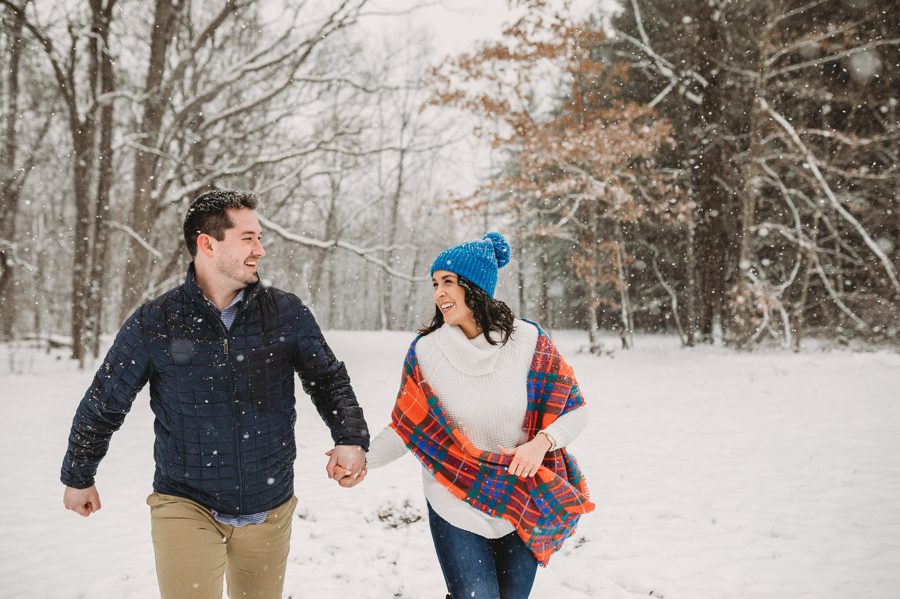 Hoover Reservoir Engagement photo of engaged couple holding hands laughing while racing in the snow