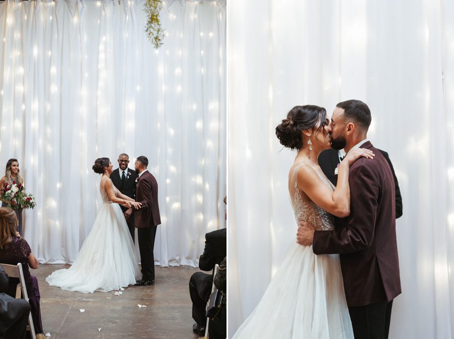 bride and groom first kiss with string lights