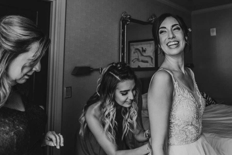 bride laughing while getting into wedding dress