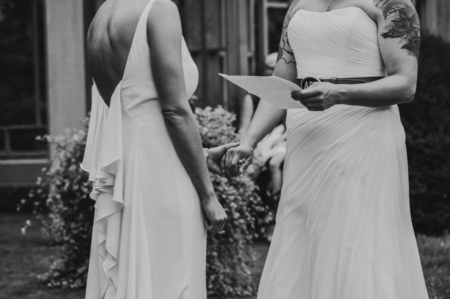 two brides holding hands during exchange of vows