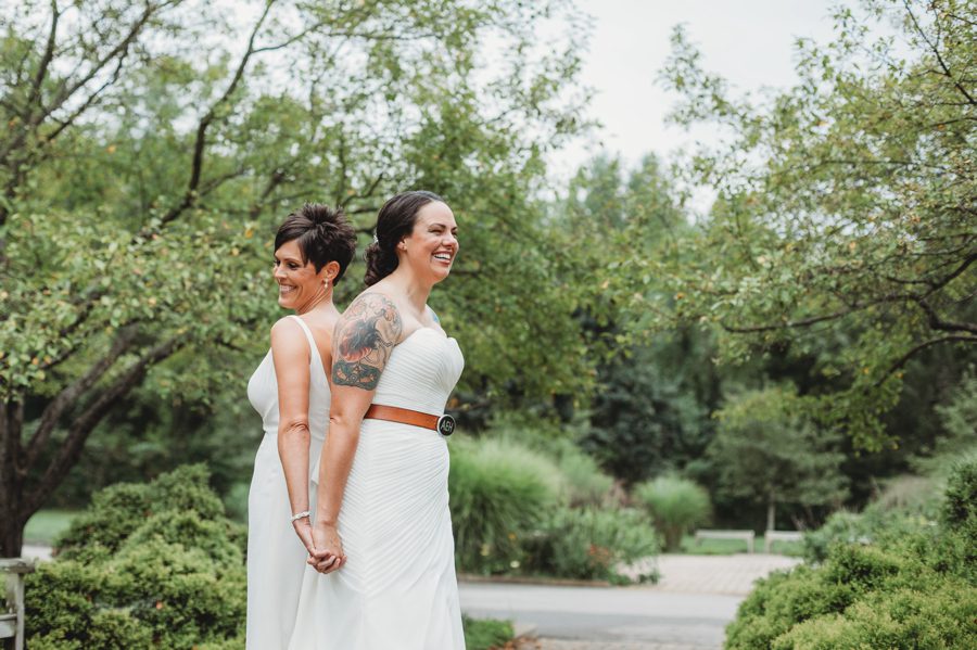 same sex female couple laughing while standing back to back